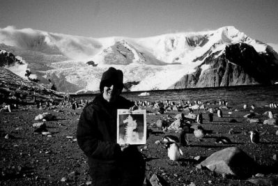 03-15-01-2
Betty Parker of Mattapoisett stands ashore on the continent of Antarctica at Neko Harbor on the Danco Coast (latitude 64 degrees, 49.5 minutes south, 62 degrees, 52.3 minutes west) posing with a copy of The Wanderer while Gentoo penguins approach in the background. The air temperature was 42 degrees, sea temperature 32 degrees  a beautiful day to land after a rough crossing of the Drake Passage. 3/15/01 edition
