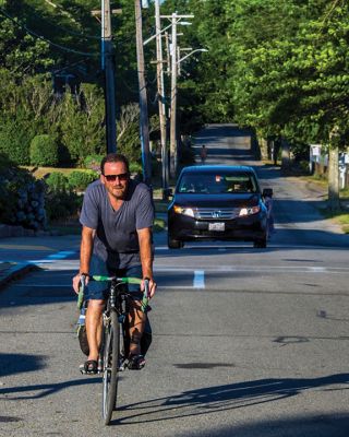 On the Road
A bicyclist rides along Water Street in Mattapoisett, while a car approaches. As more and more bicycles, cars, trucks, and joggers crowd village and rural roads, frustration and intimidation are on the rise. See story inside from which cyclists, drivers, and pedestrians can learn. Photo by Ryan Feeney - July 30, 2020 edition
