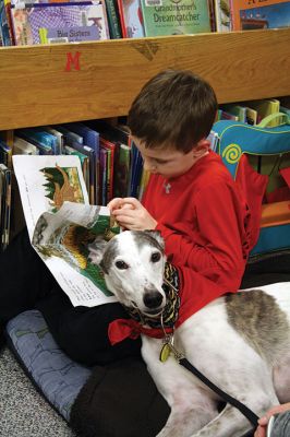Amos the greyhound 
Amos the greyhound is new to Rochester and he and his owner ‘Ms. Holly’ have been looking to find his niche in the community. Since Amos is a trained therapy dog and he loves kids and books, he decided to hold an event at the Plumb Library on Thursday, January 12. Pictured here, Owen Perry reads to Amos who snuggled in closely.

