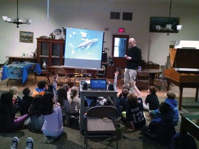 Marion Natural History Museum
Dr. Michael Moore of Woods Hole Oceanographic Institute, using the museum's harpoon and baleen, introduced the Marion Natural History Museum's after-school group to a little of Marion's whaling history. Students could ask questions and theorize why Sippican Harbor had the first recorded visit from a humpback whale this fall. We wish to thank Dr. Moore for the great program. Photo courtesy Elizabeth Leidhold
