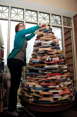 Book Tree
Liz Sherry, the Young Adult and Adult Reference Librarian at the Mattapoisett Library, puts a star on top of the book tree on Saturday, December 1.  The tree is comprised of recycled books left over from the book sale and is serving as a holiday decoration in the Young Adult section, which is currently being redesigned.  Photo by Felix Perez.
