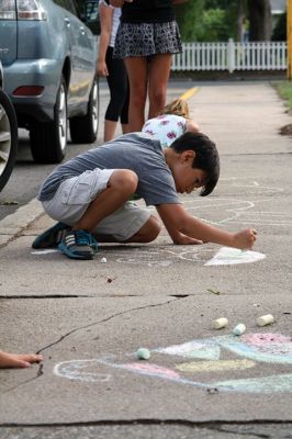 Chalk It Up
The day before the Marion Town Party, kids chalked-up the sidewalks in front of the Marion Town House in preparation for the Saturday night event. Town Party Planning Committee members set up picnic tables and strung party lights in the background while the kids drew colorful, festive pictures with chalk. Photos by Jean Perry
