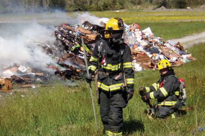 Trash Fire
A trash truck was up in smoke on Long Plain Road in Mattapoisett last week. Before I knew it, engines and firemen appeared in full gear. The Fire Department had the driver dump all the trash in a field near the road where the fire could be more safely extinguished. Photo by Ellie Higgins
