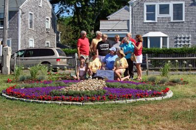 Garden Group Glory
Members of Mattapoisetts 150th Garden Group recently posed for this aerial shot of the sesquicentennial logo they recreated out of plantings at Shipyard Park. The group members have put in countless hours planting this and other beds from Shipyard Park to Neds Point to commemorate the towns 150th birthday. This photo is also being planned as the cover for the next Annual Town Report. (Photo by Robert Chiarito).
